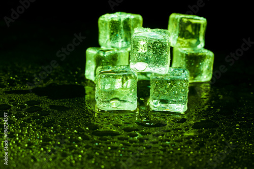 Green ice cubes on black background. © peterkai