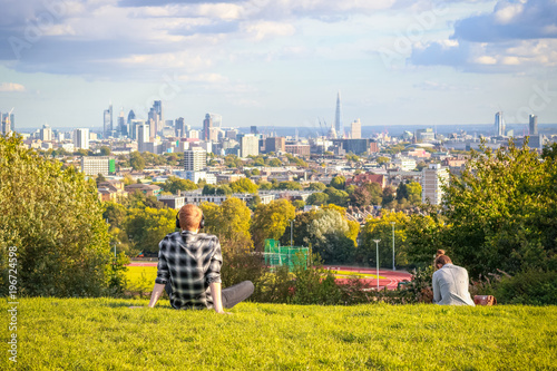 Fototapeta Back view of tourists looking over London city skyline from Parliament Hill in H
