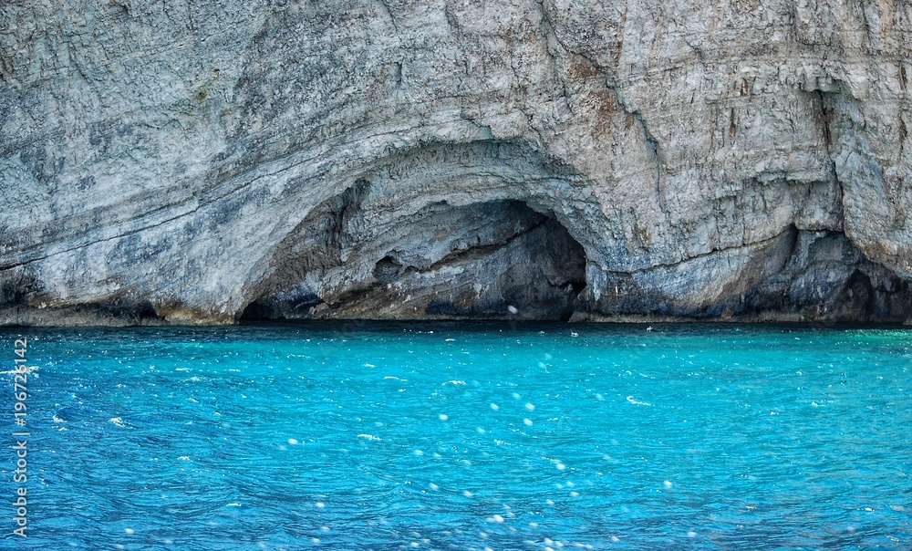 landscape cave entrance against a background of blue water