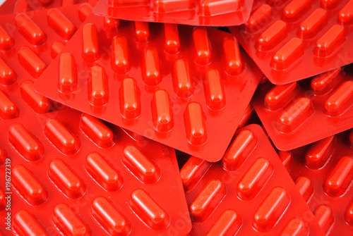 Bright red blisters with capsules closeup background