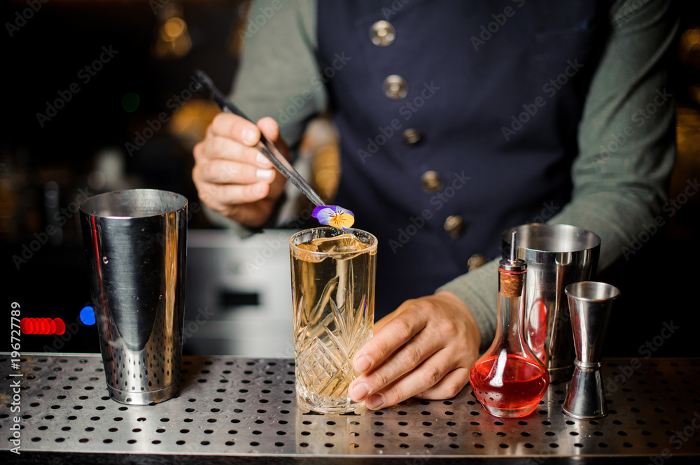 Barman decorating a sweet alcoholic cocktail with a flower