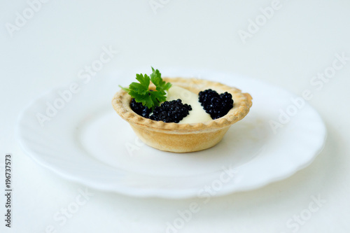 tartlet with caviar and herb on a white plate