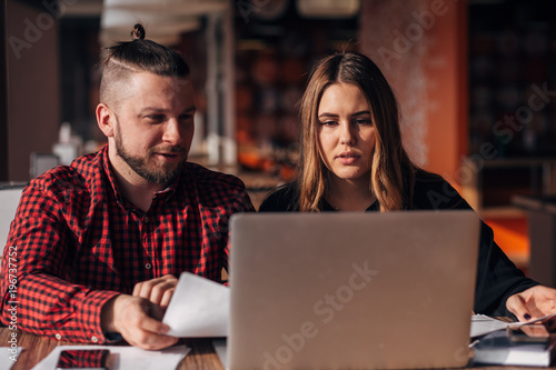 young freelancers man and woman sitting in a cafe and working for a laptop
