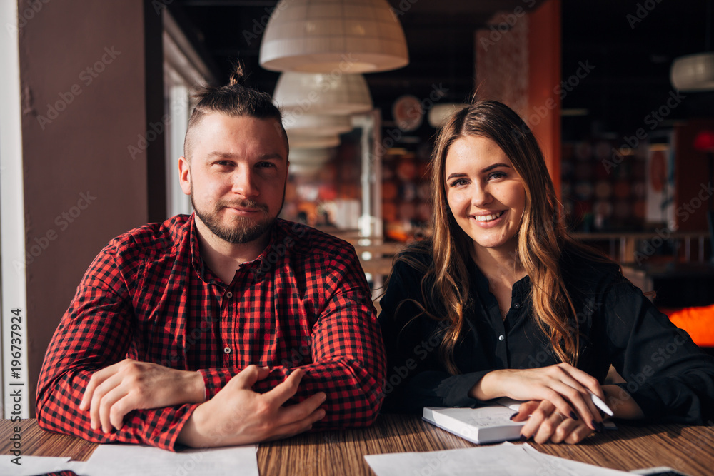 Fototapeta premium two happy freelancer smiling at camera in cafe