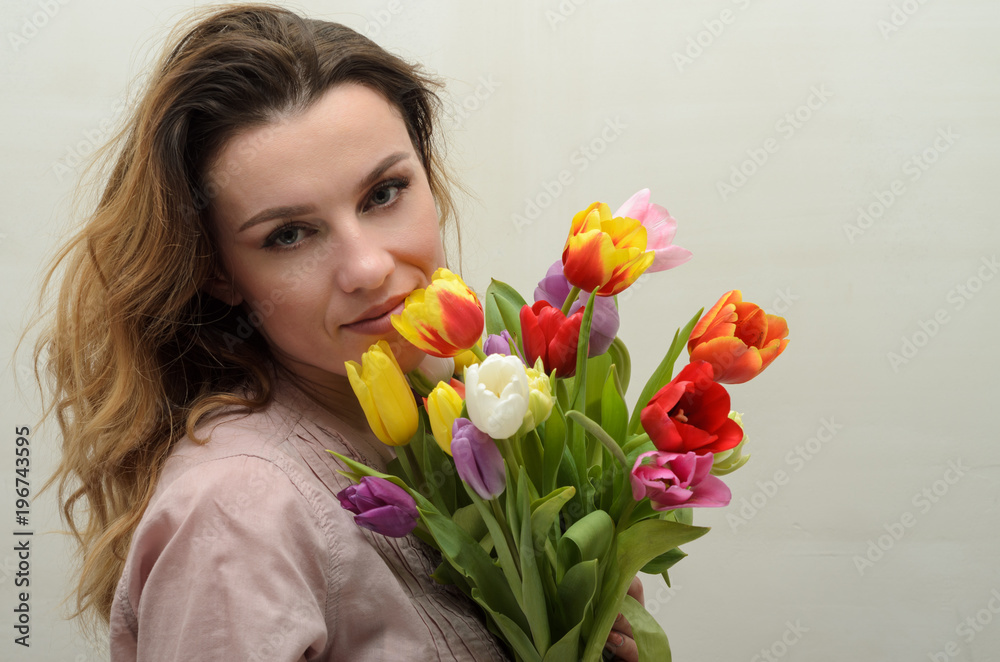 Young charming girl with a bouquet of flowers - multi-colored tulips Young charming girl with a bouquet of flowers - multi-colored tulips