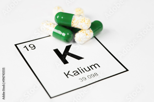 Green pills with mineral K (Kalium) on a white background with an inscription from the chemical table