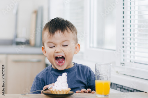 a child in the kitchen eats cake and screams with delight