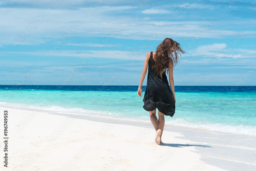 Female walking on beach with transparent water of ocean in Maldives Female walking on beach with transparent water of ocean in Maldives