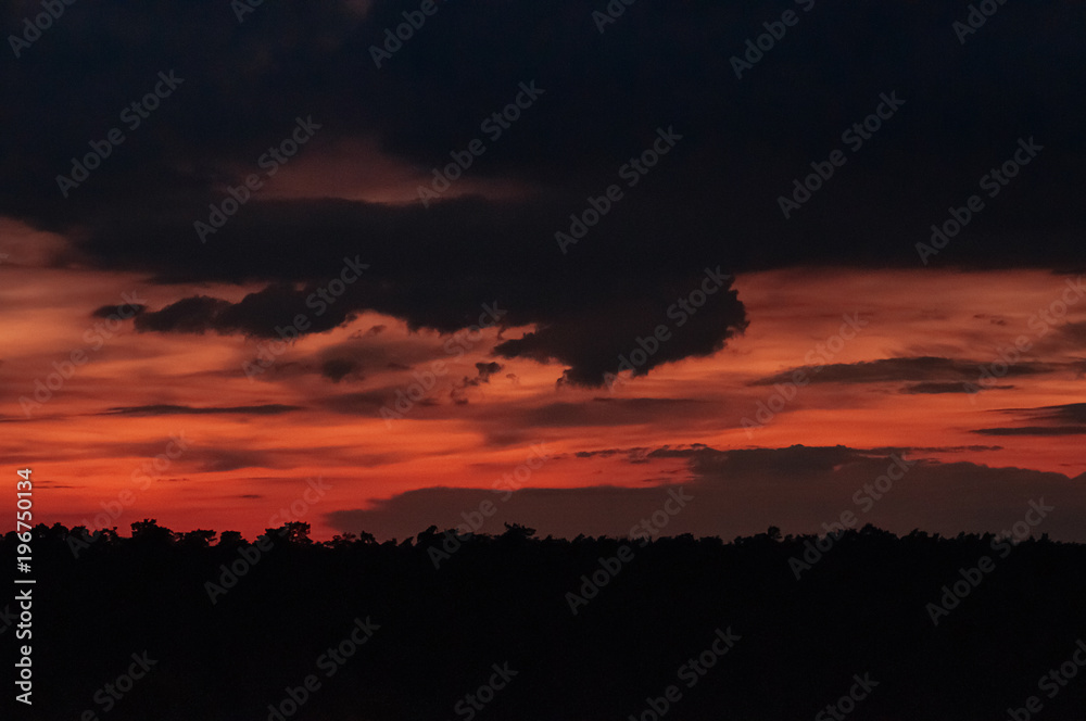 Sunset dramatic red sky with heavy dark blue rainy clouds