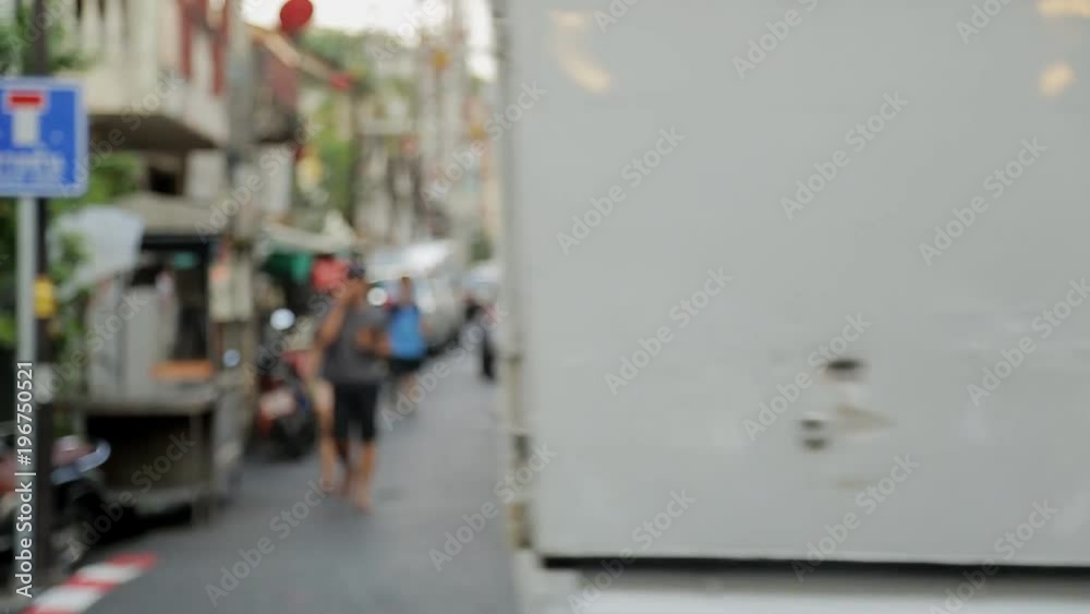 Defocused view of the city's busy street in Asia in the summer. During day all the townspeople are engaged in their own affairs in Asian country, cars are passing by. Defocused view of the city's busy street in Asia in the summer. During day all the townspeople are engaged in their own affairs in Asian country, cars are passing by.