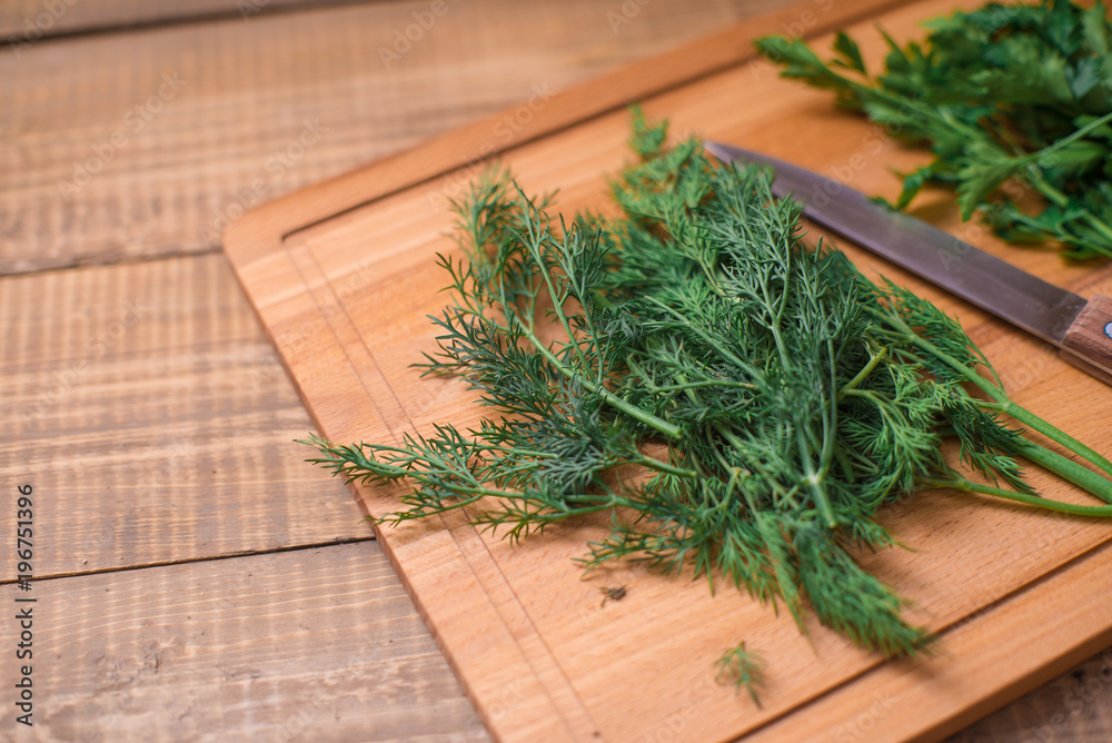 Dill and parsley on wooden board on table with knife Dill and parsley on wooden board on table with knife