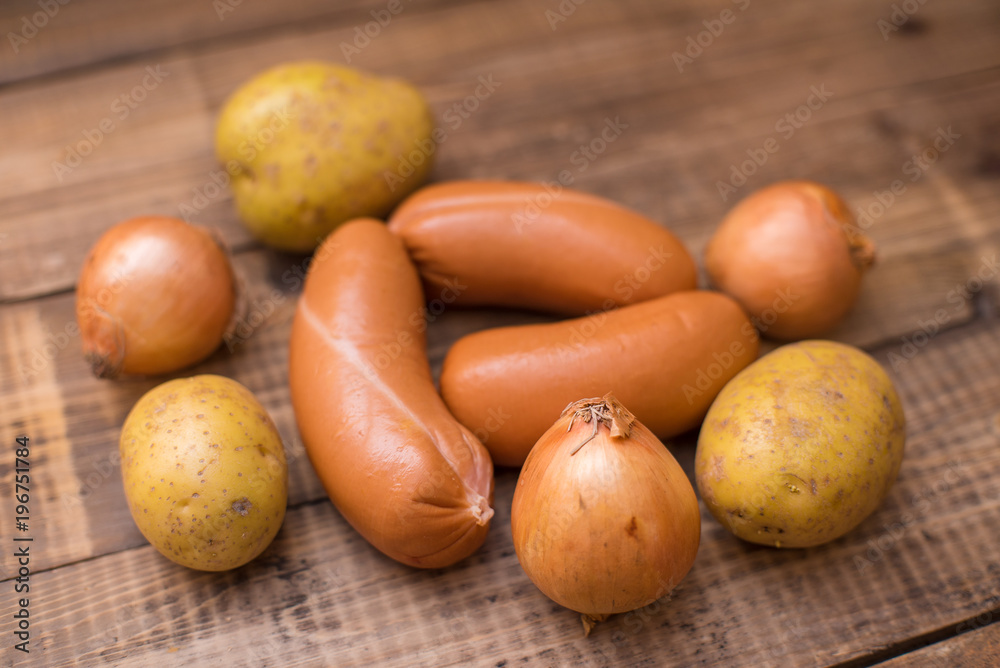 Raw sausages, potatoes and onions on wooden table Raw sausages, potatoes and onions on wooden table