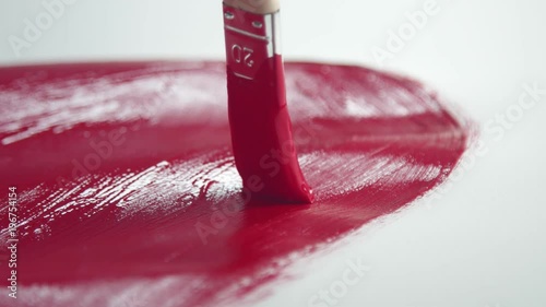 closeip macro of painting brush with red color acryl paint on white paper photo