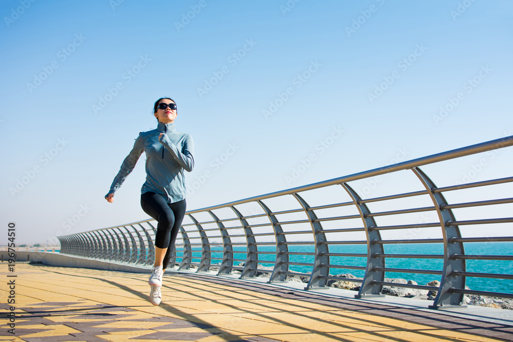 Girl jogging on the boardwalk by the sea