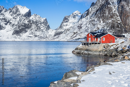 Red fisherman´s house on Lofoten islands in front of a fjord at a beautiful sunny winter day