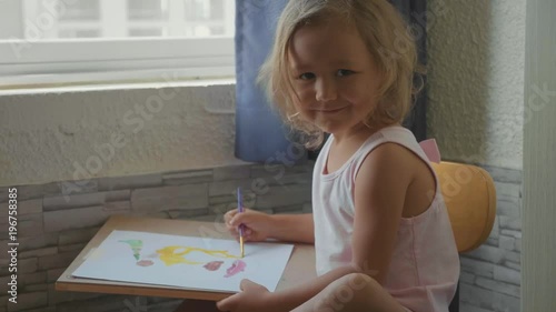 Child girl drawing by watercolor at home in slow motion. photo