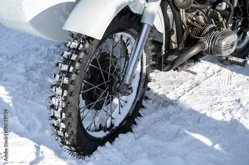 Motorcycle racing in the snow.Heavy white motorcycle on a white snowy road. A fragment of a close-up.