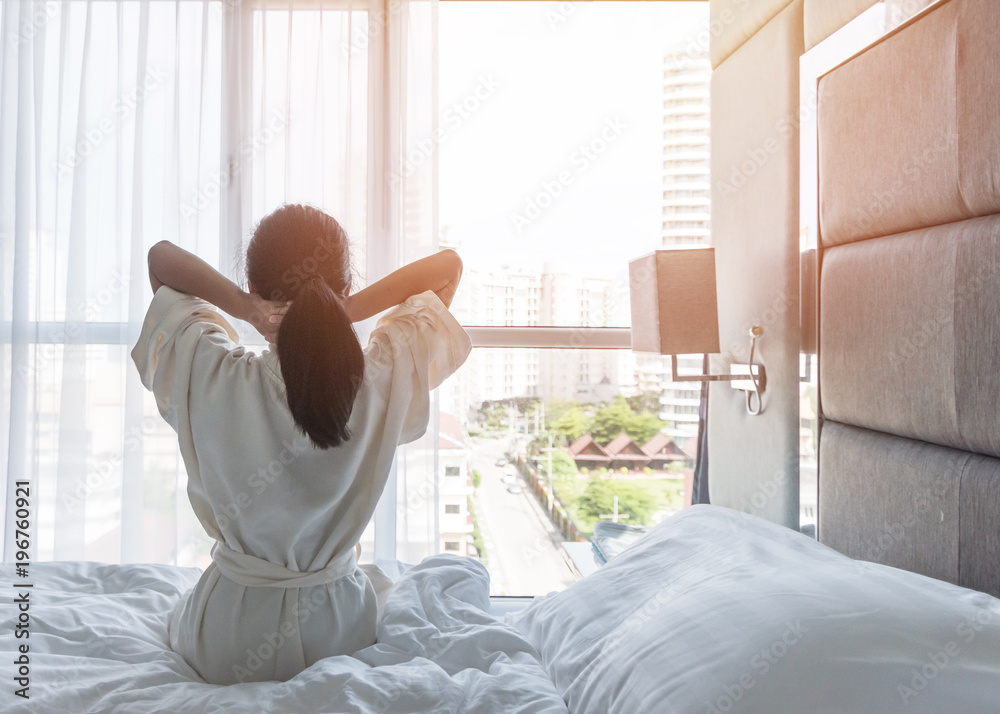 Easy lifestyle Asian woman waking up from good sleep in weekend morning taking some rest, relaxing in comfort bedroom at hotel window, having happy lazy day enjoying work-life quality balance concept Easy lifestyle Asian woman waking up from good sleep in weekend morning taking some rest, relaxing in comfort bedroom at hotel window, having happy lazy day enjoying work-life quality balance concept