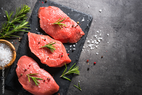 Beef steak with rosemary and spices on black background