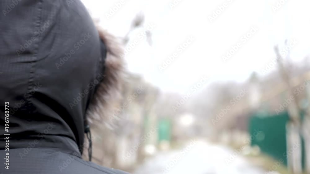 Close up of unrecognisable man wearing a hood and walking on the road. Shot in slow motion from behind Close up of unrecognisable man wearing a hood and walking on the road. Shot in slow motion from behind