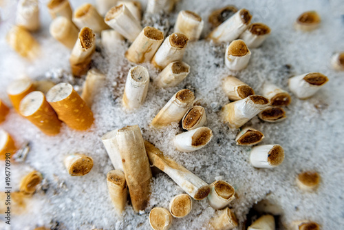 Some Squeezed cigarettes in an ashtray in winter with snow