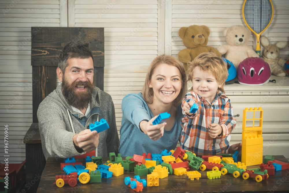 Naklejka premium Young family play game with construction plastic blocks.