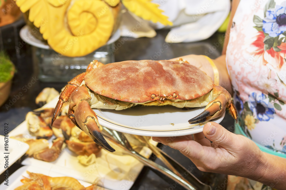Big red crab on a plate in the hands of a girl Big red crab on a plate in the hands of a girl