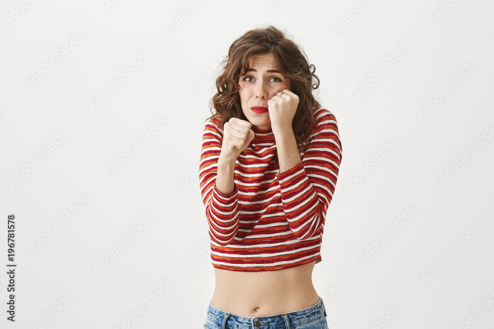 Tight cropped face of a scared young girl with hands covering