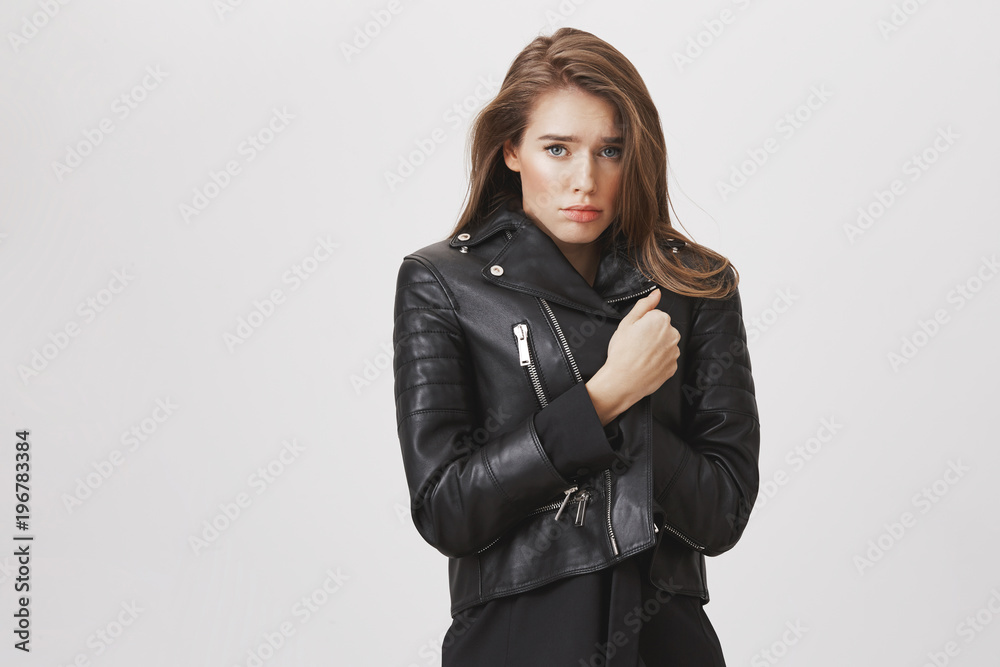 Gloomy girlfriend feeling like stray kitten. Sad attractive caucasian woman pulling leather jacket tightly, feeling cold and upset during walk with boyfriend who offended her with lack of attention