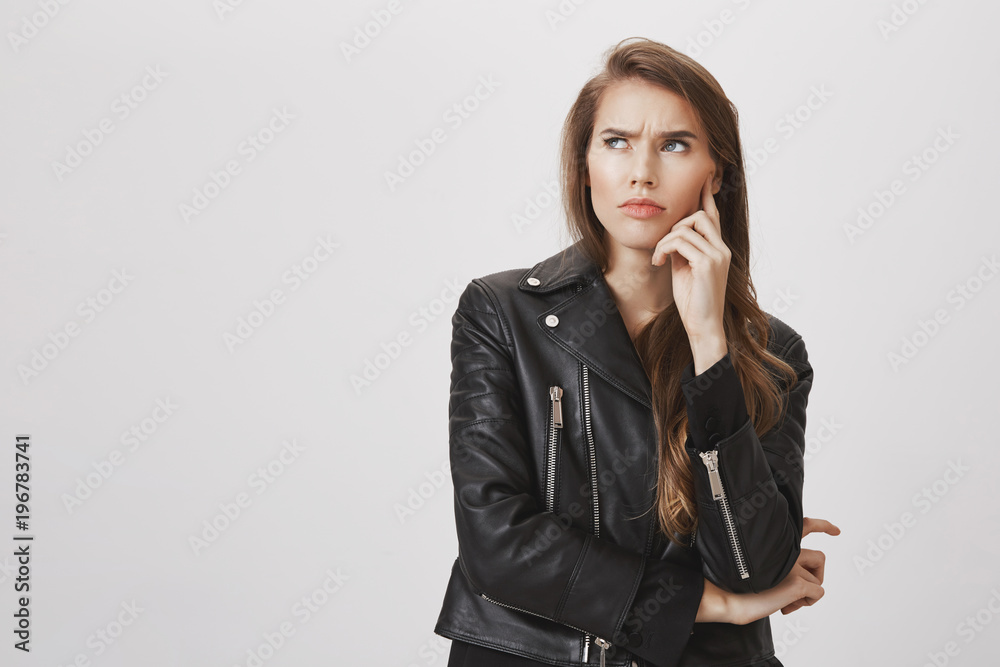 Hard question bothered her mind. Portrait of confused and doubtful good-looking woman looking up, frowning, holding hand on cheek, thinking about issue, searching solution of problem over gray wall Hard question bothered her mind. Portrait of confused and doubtful good-looking woman looking up, frowning, holding hand on cheek, thinking about issue, searching solution of problem over gray wall
