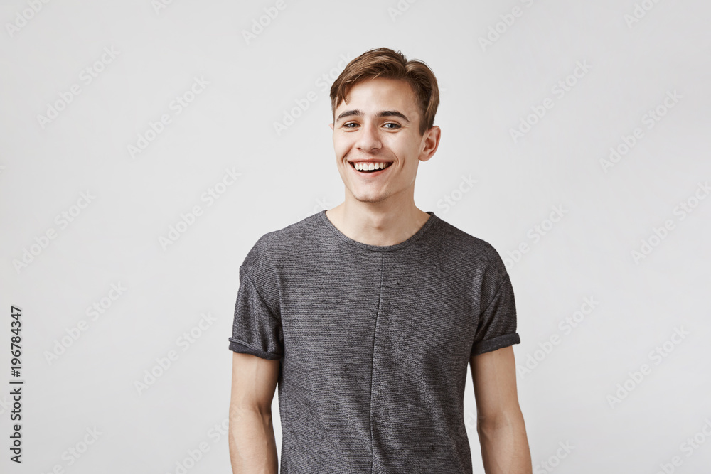 Handsome young brunette with kind eyes tries to use all his charm and beautiful smile to ask his boss for a day off. Women in an office can not resist him so he already thinks how to spend free day - obrazy, fototapety, plakaty 