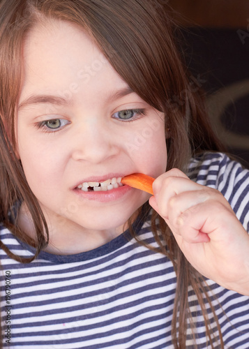  A cute Caucasian child is eating carrots.