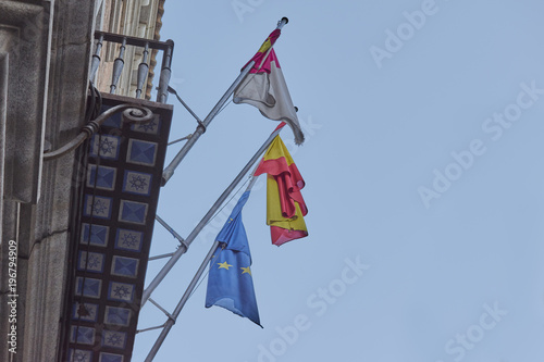 Flags of Europe, Spain and Castilla La Mancha on masts subject on a balcony with blue sky background
