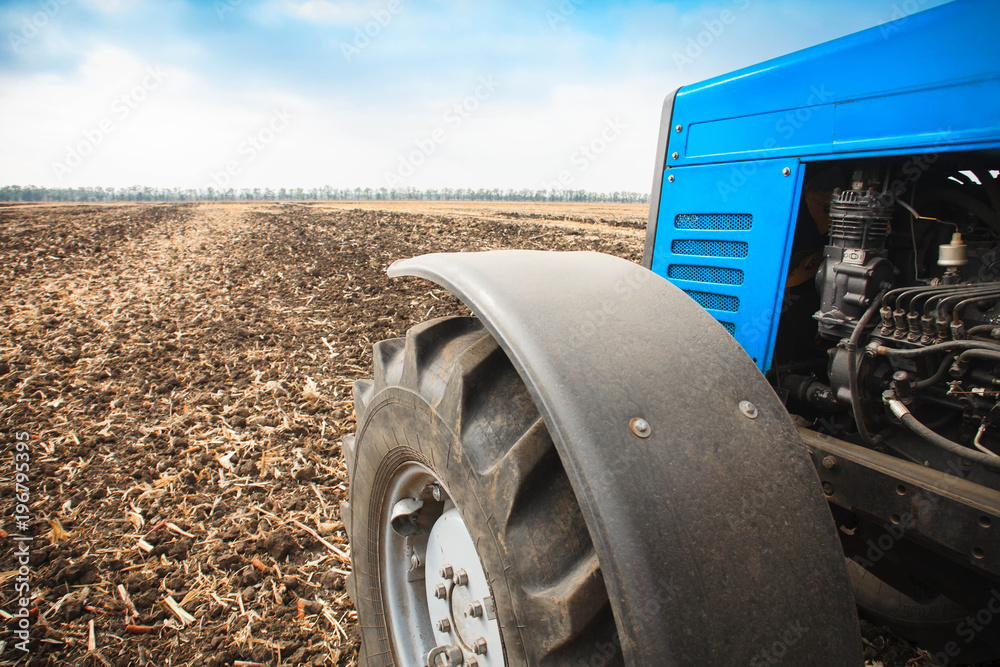 Obraz premium Old blue tractor close-up in a empty field. Agricultural machinery, field work.