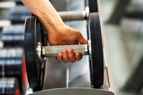 Hand grabs dumbbell in modern gym