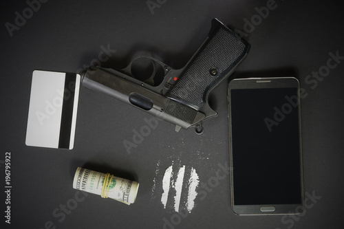 Mobile phone, powder drug like cocaine, gun, credit card and money on black table