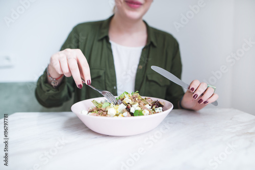 Girl's hands with cutlery over a plate of salad. A girl eats a salad with a fork and a knife. Healthy Eating