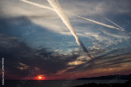 traces of airplane flying in the cloudy sky at sunset