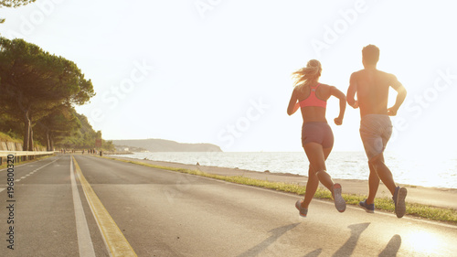 Canvas Print COPY SPACE: Athletic young couple jogging near the sea on perfect day in summer