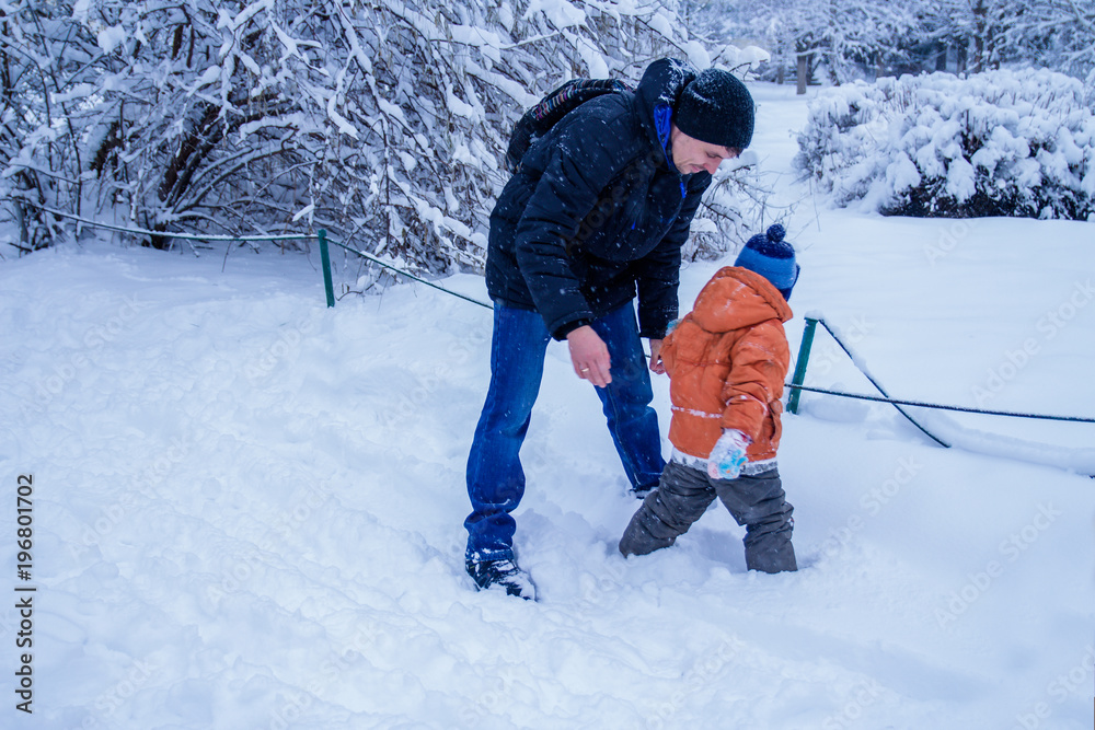 Father and his son playing outside, winter forest on the background, snowing, happy and joyful