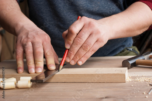 carpenter makes the marking of the wooden part in red pencil