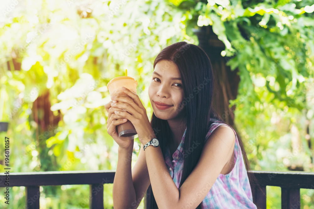 young woman is drinking coco or coffee in the garden and relax with her sunny day. young woman is drinking coco or coffee in the garden and relax with her sunny day.