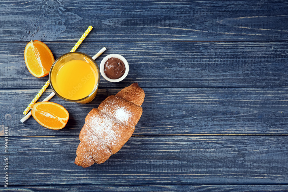 Composition with fresh tasty crescent roll and orange juice on wooden background Composition with fresh tasty crescent roll and orange juice on wooden background