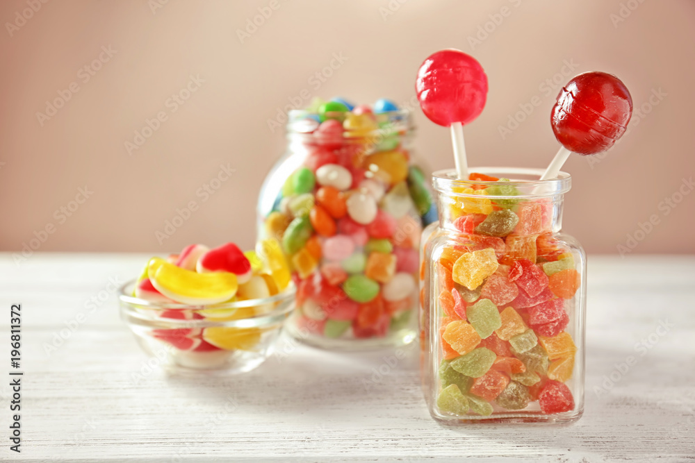 Glassware with colorful candies and succades on table against light background Glassware with colorful candies and succades on table against light background