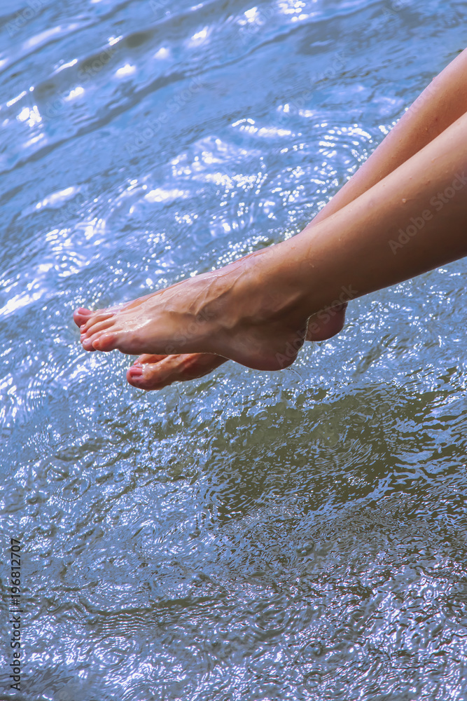 Relaxation. Young woman wets feet in water. (summer, rest, holiday, vacation concept)
