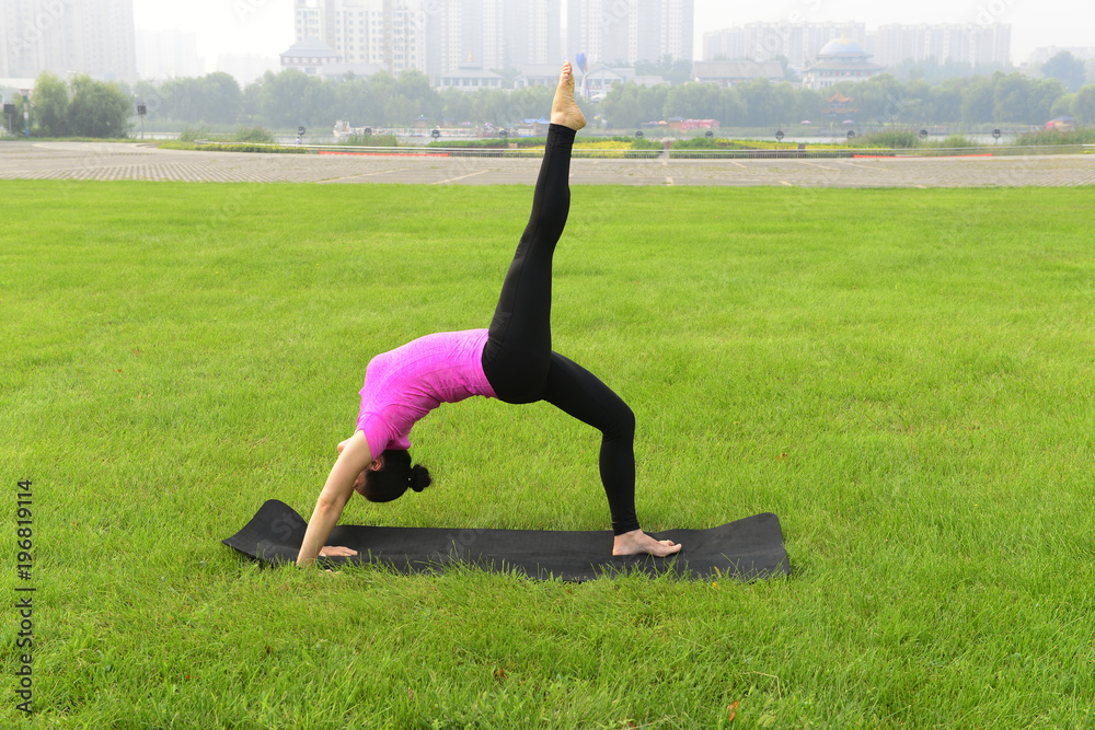 Fototapeta premium Luanan county - September 4, 2016, a woman is doing yoga training in the grass of the park, hebei, China