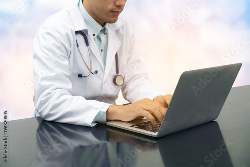 Doctor working on desk with laptop photo