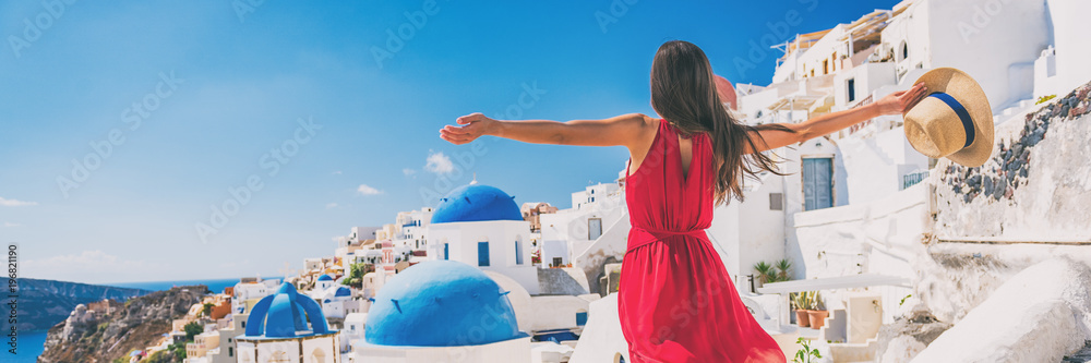 Fototapeta premium Europa podróży wakacje zabawy lata kobieta czuje bezpłatnego tana z rękami otwiera w wolności przy Oia, Santorini, Grecja wyspa. Beztroska dziewczyna turystyczny transparent panorama.