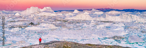 Greenland travel hiker tourist man trekking at sunset. Adventure expedition in the arctic ocean, ice floating from icebergs in ocean. Banner panorama. photo