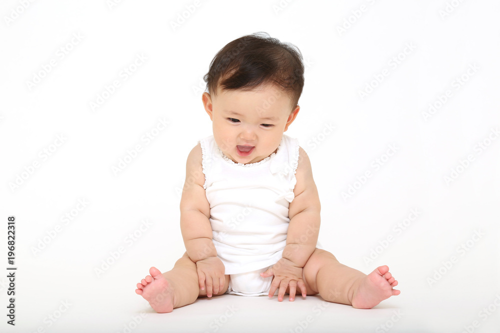 白バックの前に一人座り遊ぶ女の子の赤ちゃん Stock Foto Adobe Stock